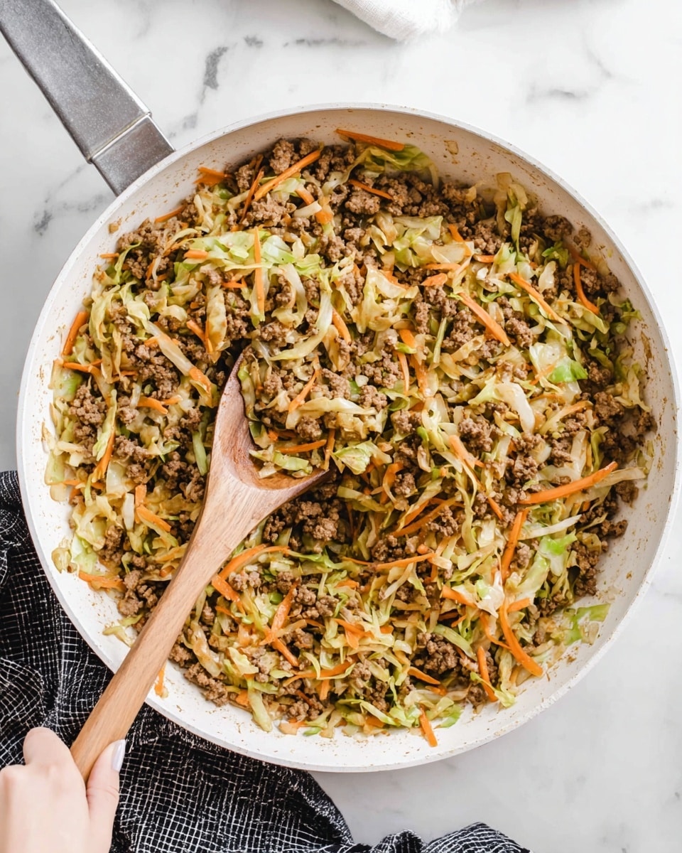 A large white pan filled with a mix of cooked ground meat and finely shredded vegetables, mostly light green cabbage and thin orange carrot strips, all slightly browned and mixed evenly. A wooden spoon is lifting a spoonful of the mixture, showing the texture of the soft cabbage and crumbly meat together. The pan sits on a white marbled surface with a black and white checkered cloth partially under it. A woman's hand is holding the pan from the bottom left corner. Photo taken with an iphone --ar 4:5 --v 7
